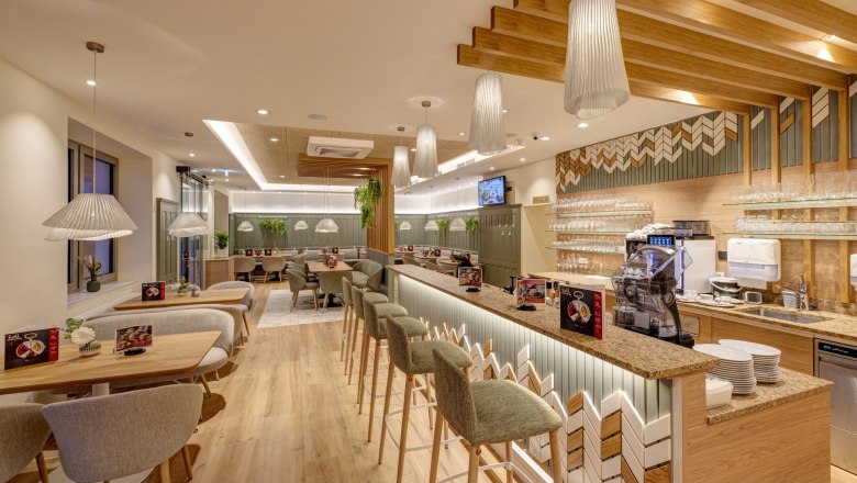 Modern café area with wooden furniture and bar.