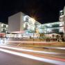 Night shot of a modern building complex with glass fa&ccedil;ade and illuminated interiors.