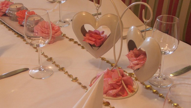 Festively laid table with heart decorations and rose petals.