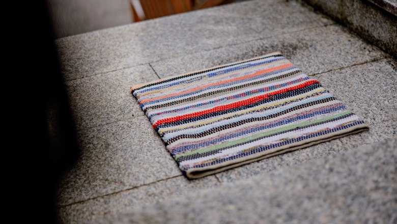 A colorful, striped carpet lies on a gray stone staircase.
