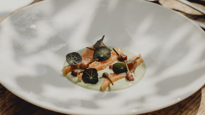 A plate with salmon trout, nasturtium cream, nasturtium leaves and chive buds.