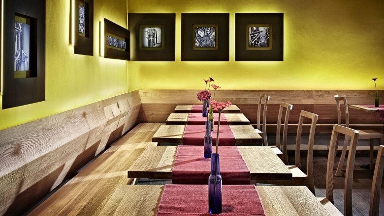 Interior view of a modern restaurant with wooden furniture and yellow walls.