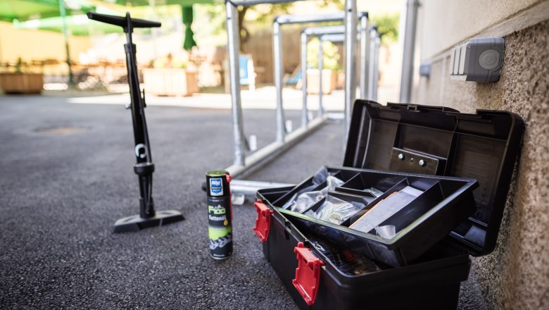 Bicycle tools, chain oil and pump next to bicycle racks outside.