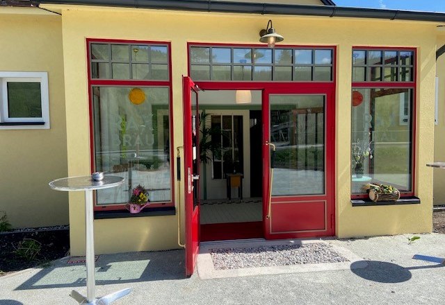 Entrance to a building with red door and window frames.