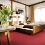 A cozy double room with a wooden bed, red carpet and a table with a bouquet of tulips.