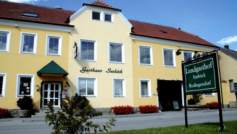 Yellow building with the inscription 'Gasthaus Surböck' and a green sign 'Landgasthof Surböck Rodingersdorf'.