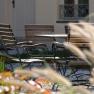 An inner courtyard with a table and chairs made of wood and metal, surrounded by plants and a building in the background.