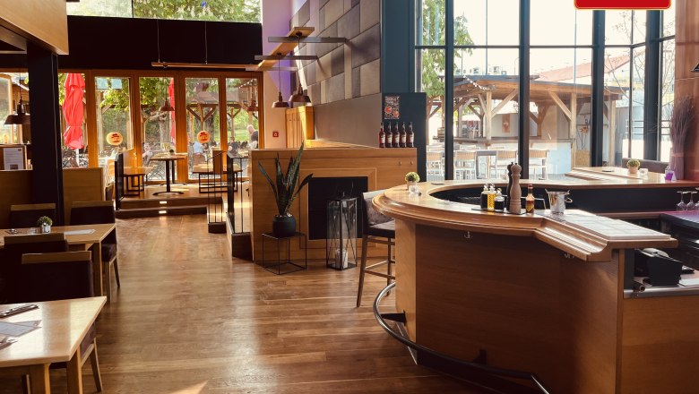 Interior view of a modern brewery with wooden furniture and large windows.