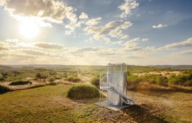 Observation tower in a rural landscape at sunset.