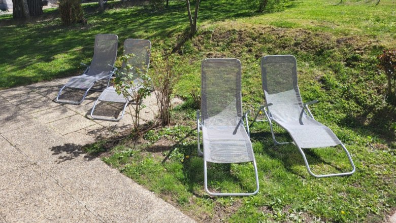 Four sun loungers on a terrace in the garden.