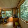 Interior view of a cozy tree house lodge with wooden walls, large windows and seating area.
