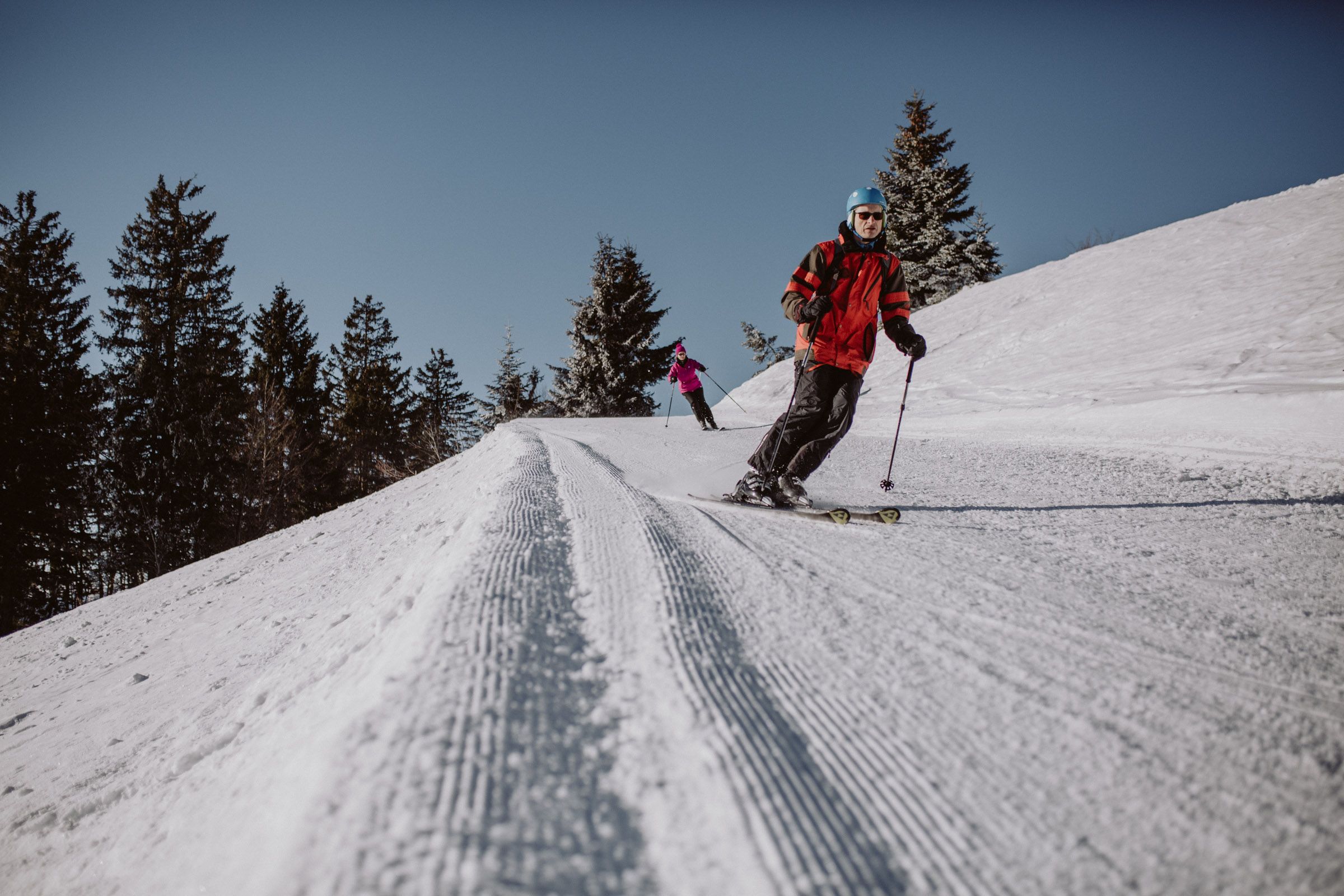 Two skiers on a groomed slope in the Unterberg ski area.
