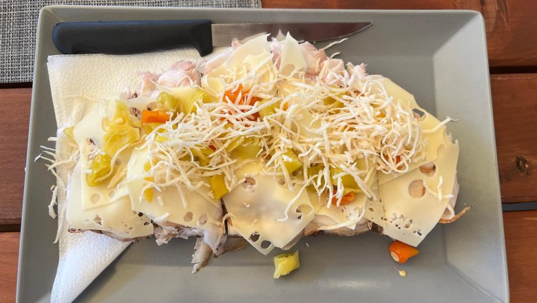 A cheese sandwich with vegetables and grated horseradish on a gray plate.