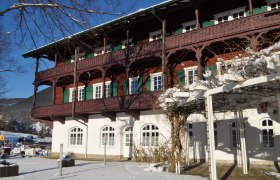 A traditional building with wooden decorations in winter, surrounded by snow and blue skies.
