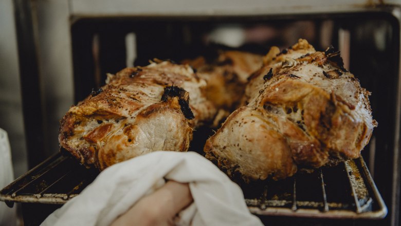 Freshly roasted pork is taken out of the oven.