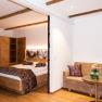 Comfortable hotel room with wooden furniture, double bed, sofa and small table.