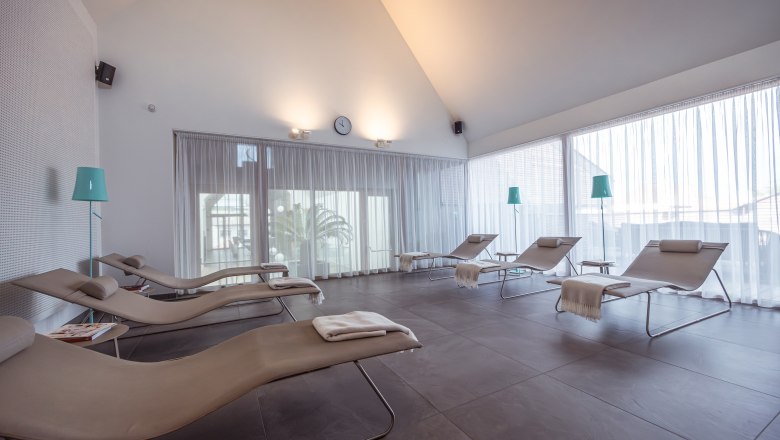 A bright relaxation room with loungers and curtains.