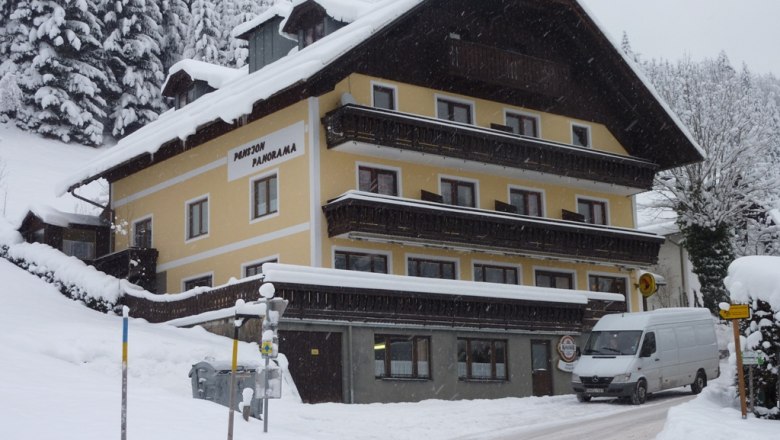 A snow-covered building with the inscription 'Pension Panorama' in a wintry landscape.