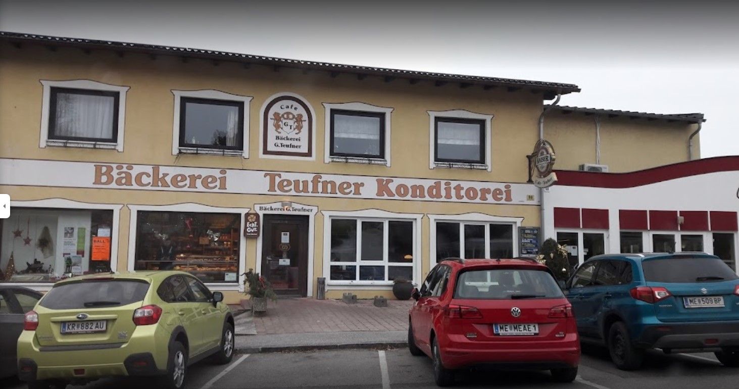 Exterior view of the Teufner bakery with parked cars in front of it.