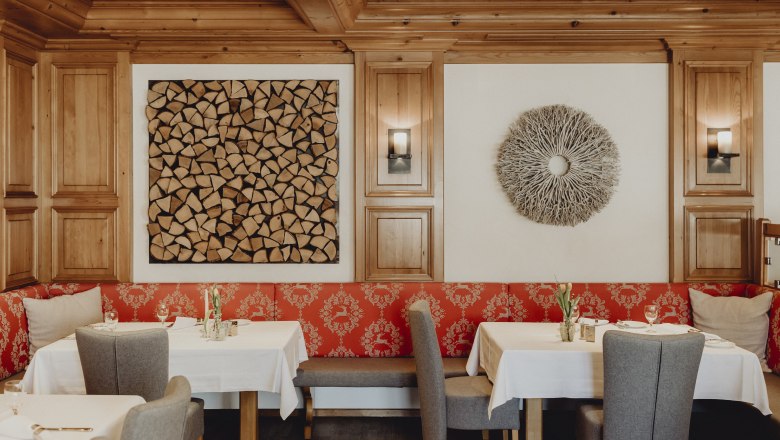 A stylishly furnished restaurant area with wooden walls, red upholstery and decorative wall art.
