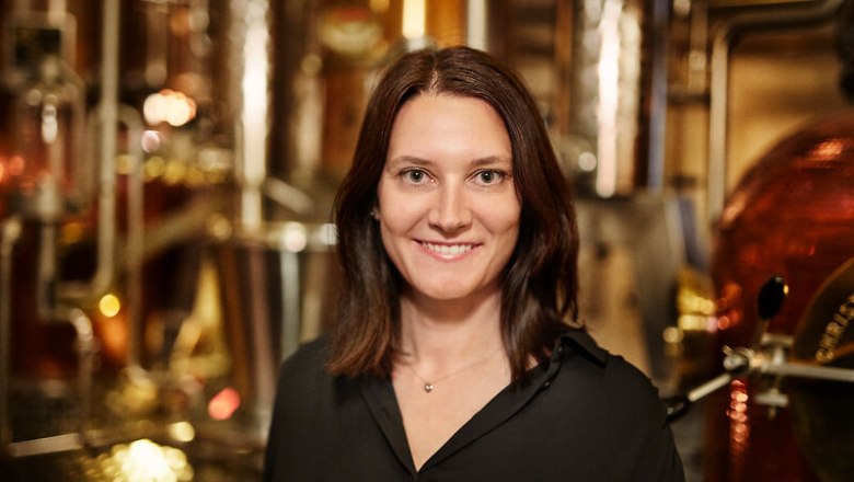 Woman in black blouse in front of distillation apparatus in a whisky distillery.