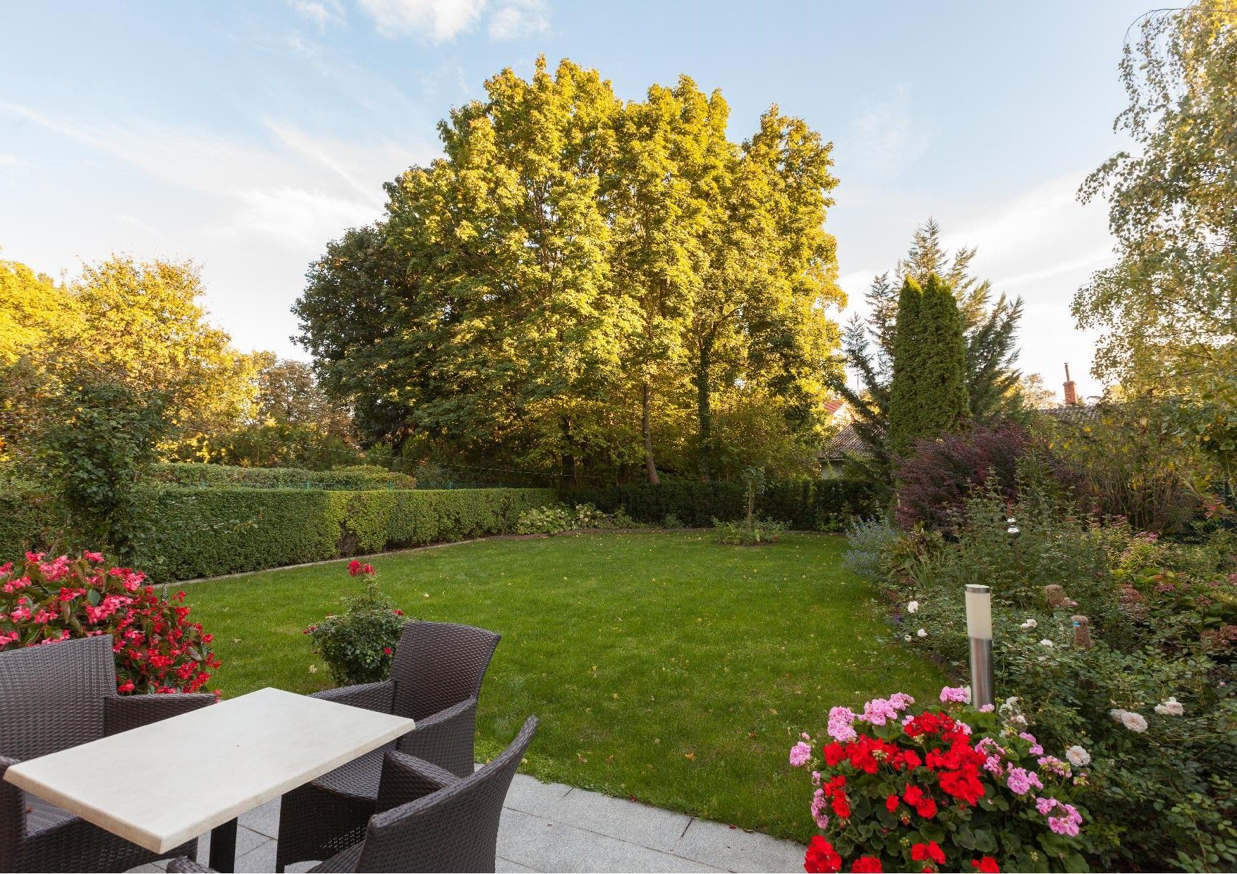 A well-kept garden with lawn, flower beds and garden furniture on a terrace.