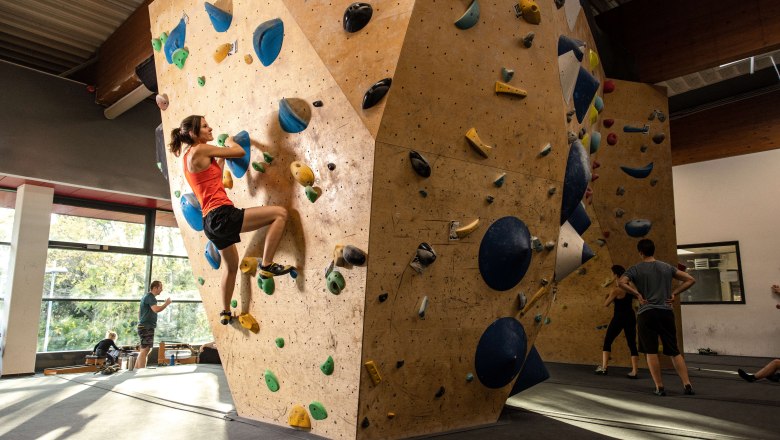Person climbing on an indoor climbing wall with colorful holds.