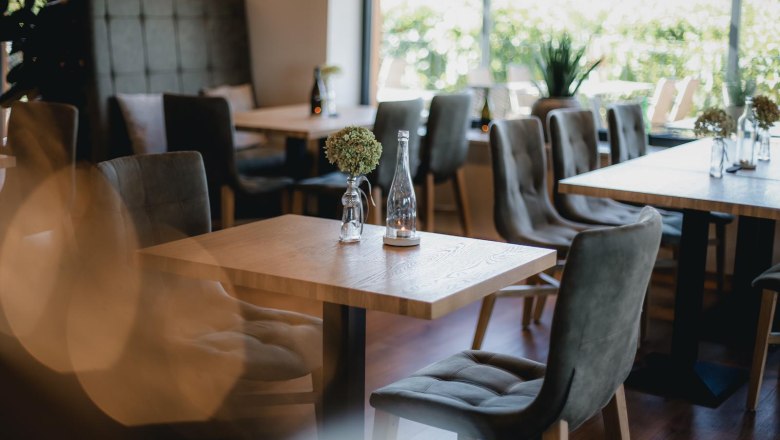 Interior view of a modern wine terrace with wooden tables and upholstered chairs.