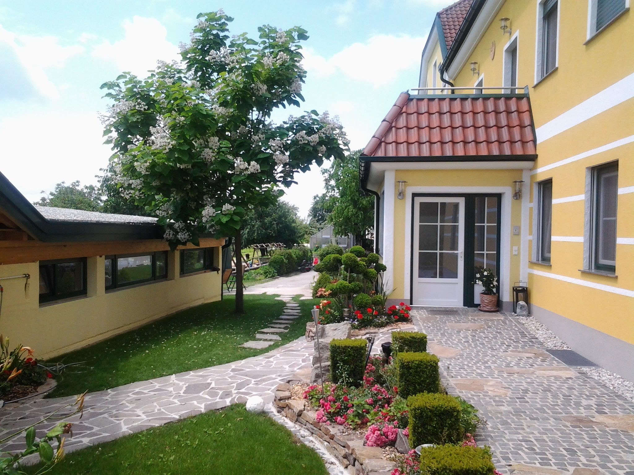 Entrance to a yellow building with a well-kept garden and paved path.