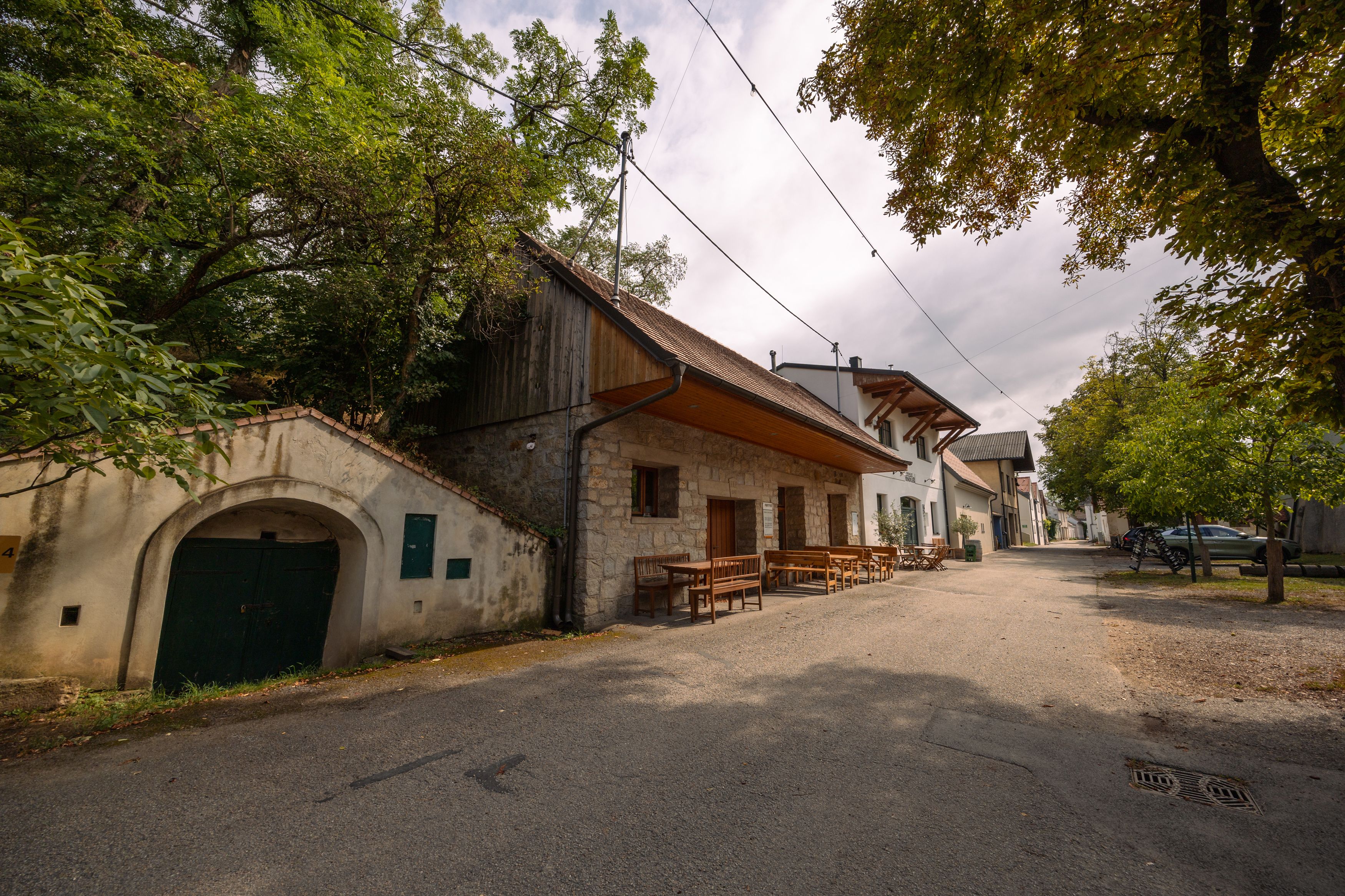 Weinviertler Kellerstöckl with rustic buildings and trees.