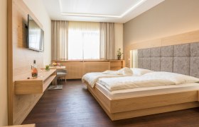 Modern guest room with double bed, flat screen TV and wooden furniture.