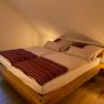 Cozy double room with wooden bed and striped bed linen.