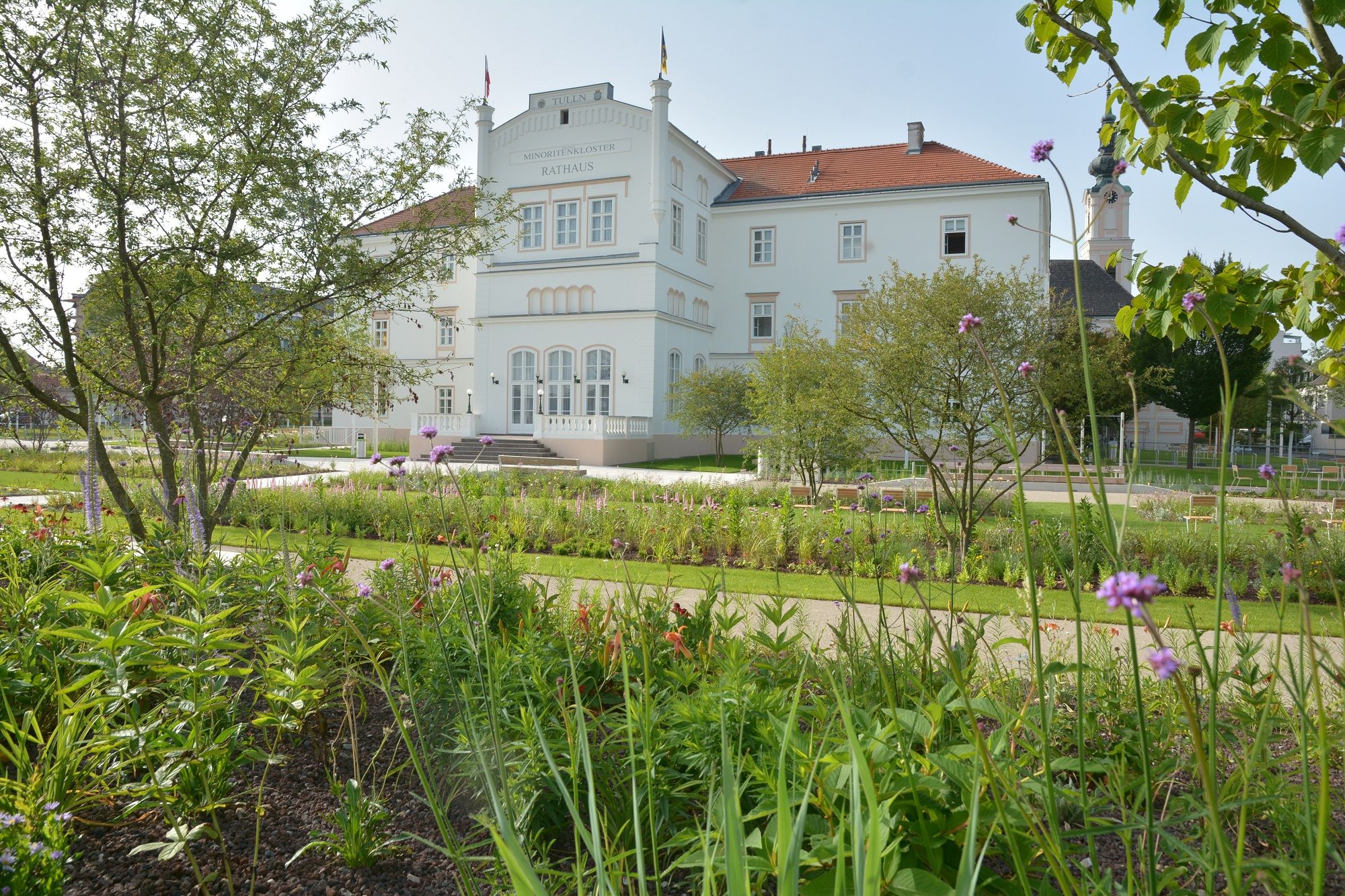 The Minoritenkloster in Tulln with a well-tended garden in the foreground.