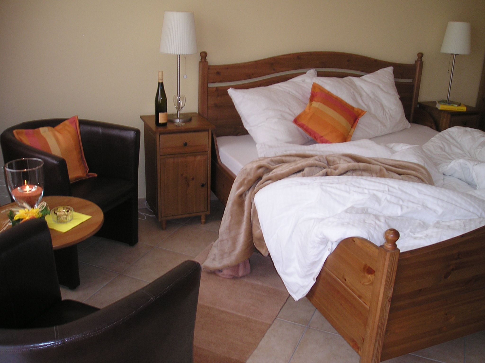 Cozy guest room with double bed, bedside table, lamp, armchair and table.