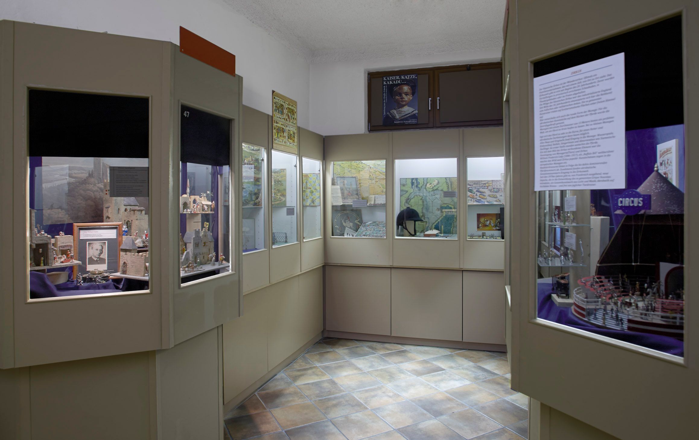 Interior view of a museum with display cases full of pewter figures and historical maps.