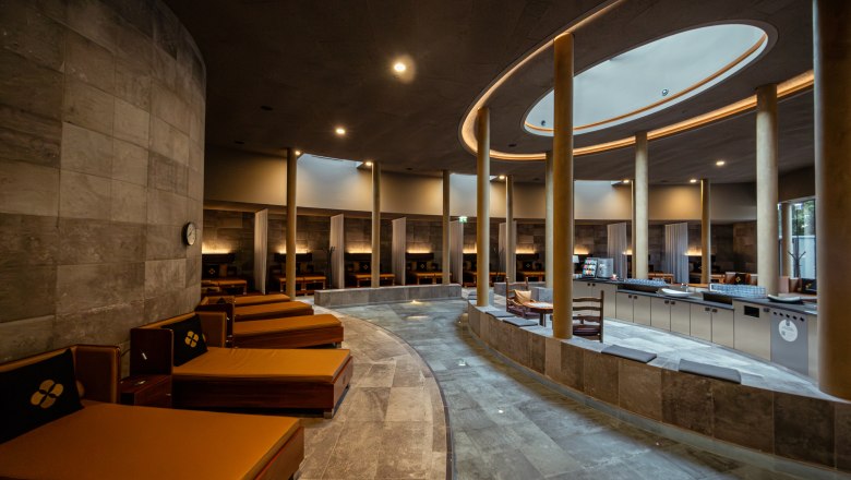 Interior view of a modern spa area with loungers and pillars.