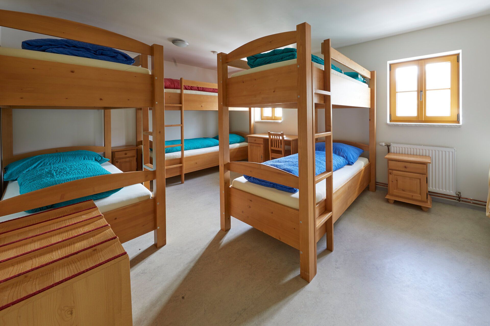 Multi-bed room with bunk beds and wooden furniture.