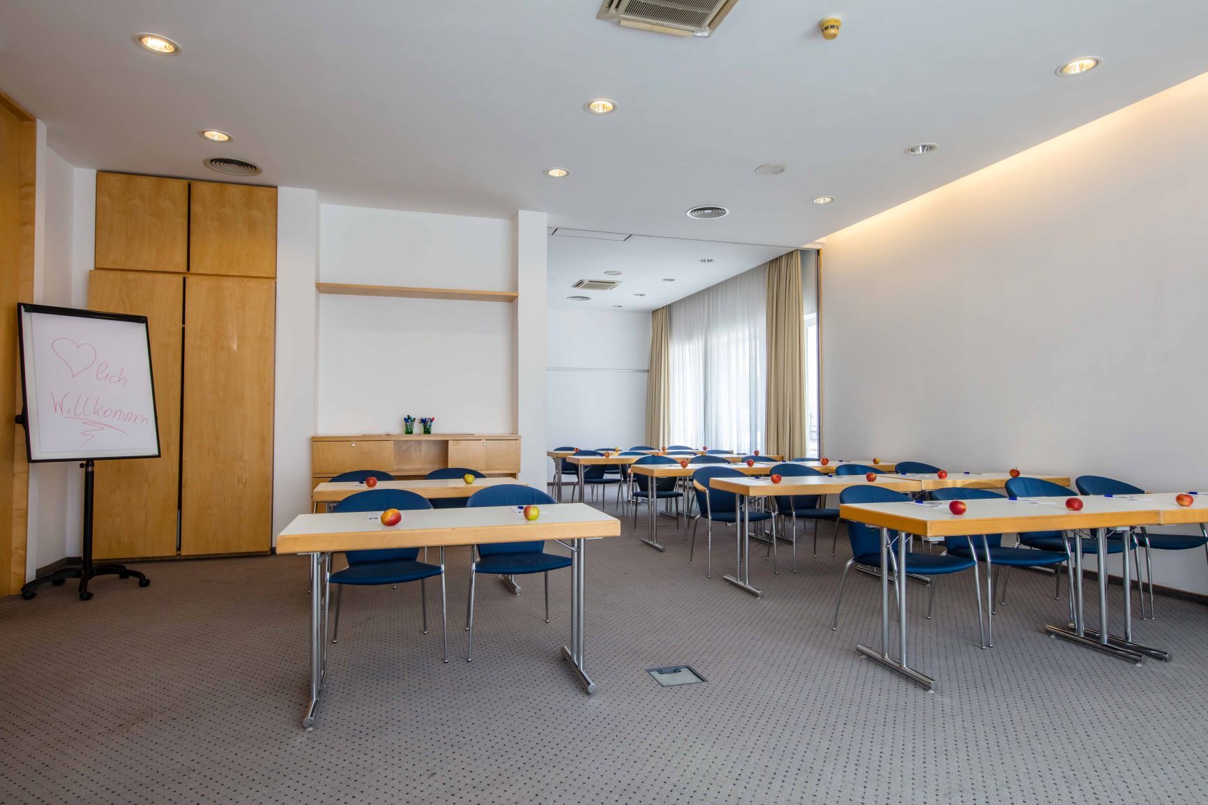 A seminar room with tables, chairs and apples on the tables.