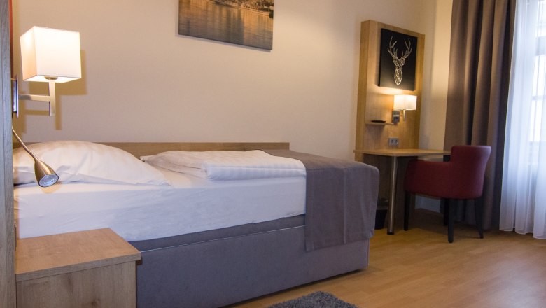 Single room with bed, desk and red chair.