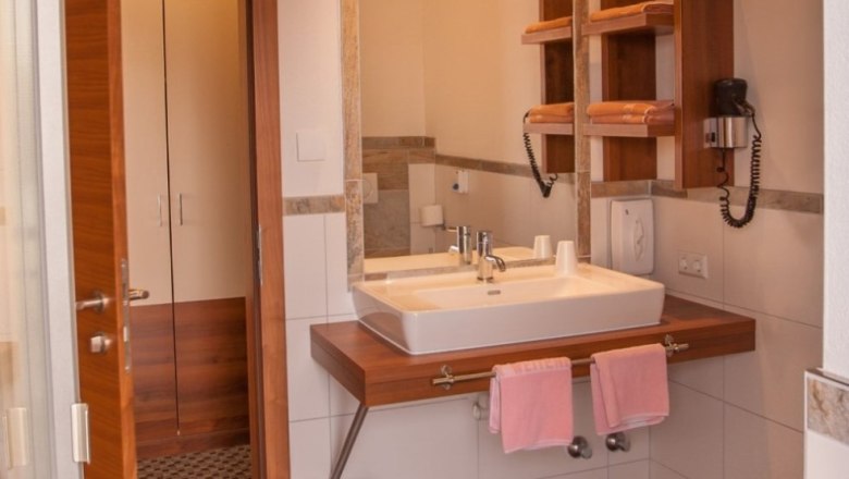 Modern bathroom with washbasin, mirror, towels and hairdryer.