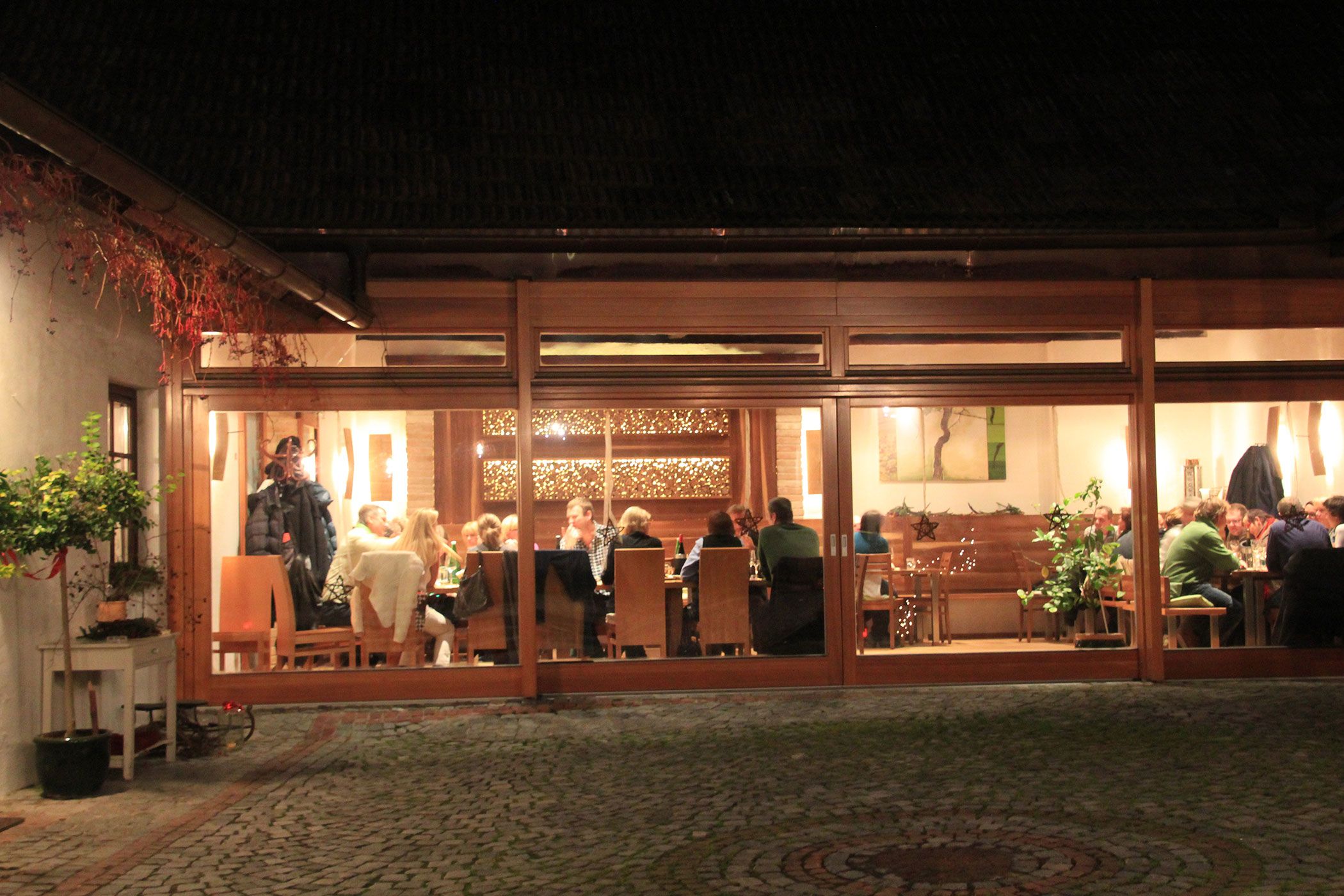 A cozy wine tavern with guests sitting at tables, visible through large windows.