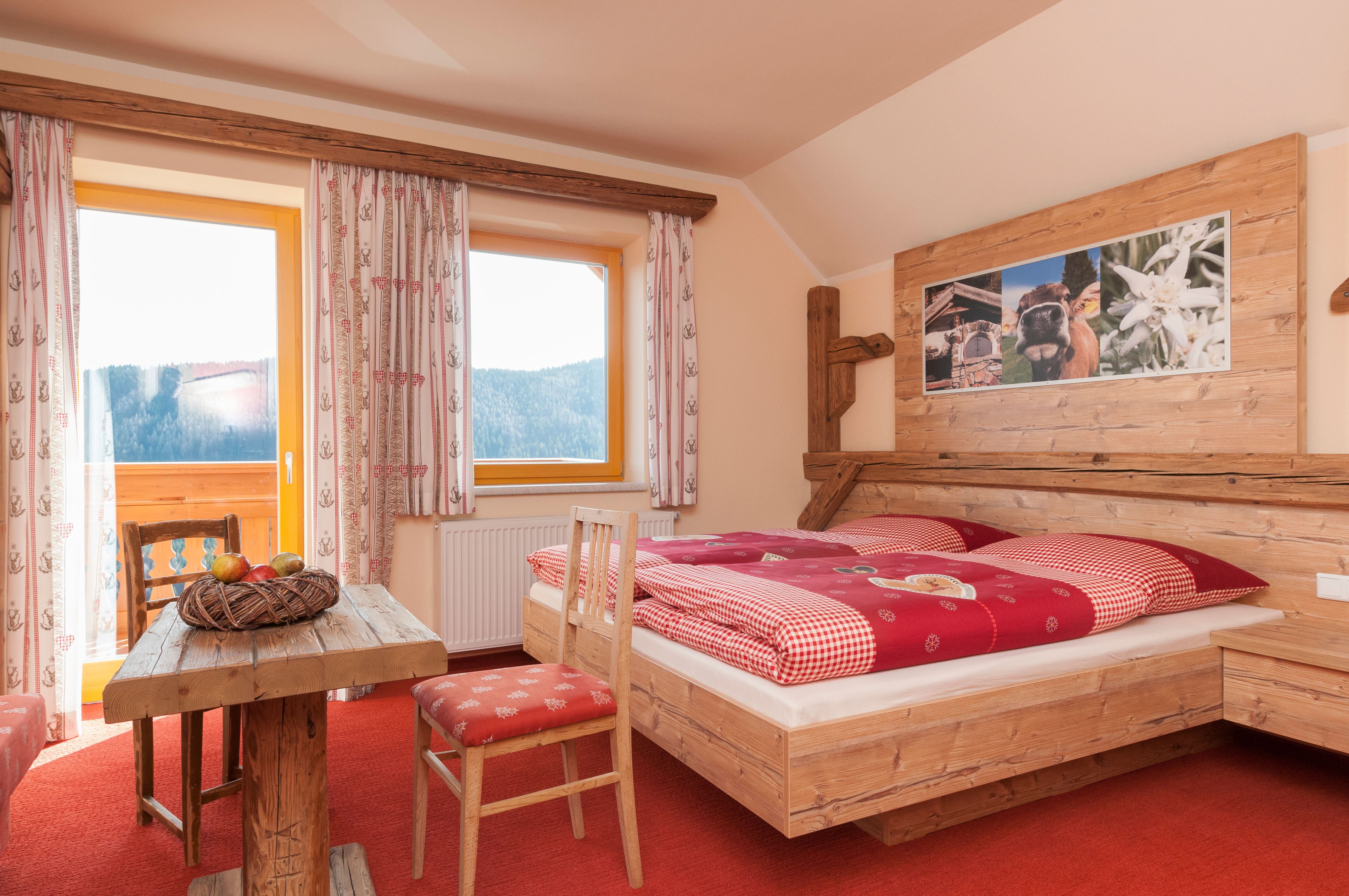 Cozy room in alpine style with wooden furniture, red carpet and mountain view.