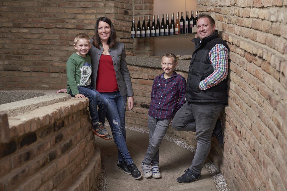A family stands in front of a brick wall in a wine cellar.
