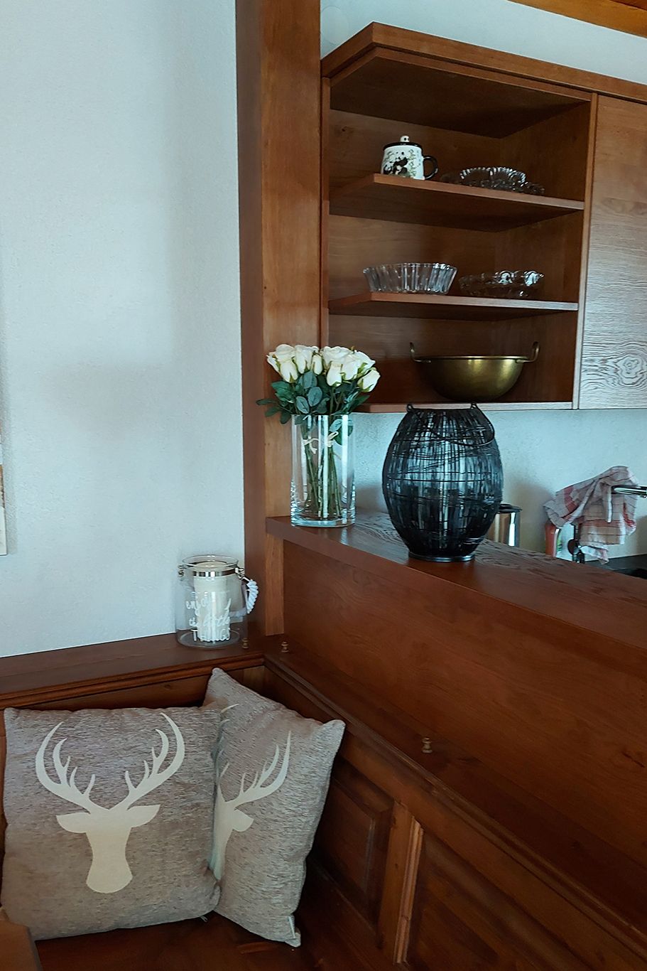 Wooden kitchen with shelves, cushions and decorations.