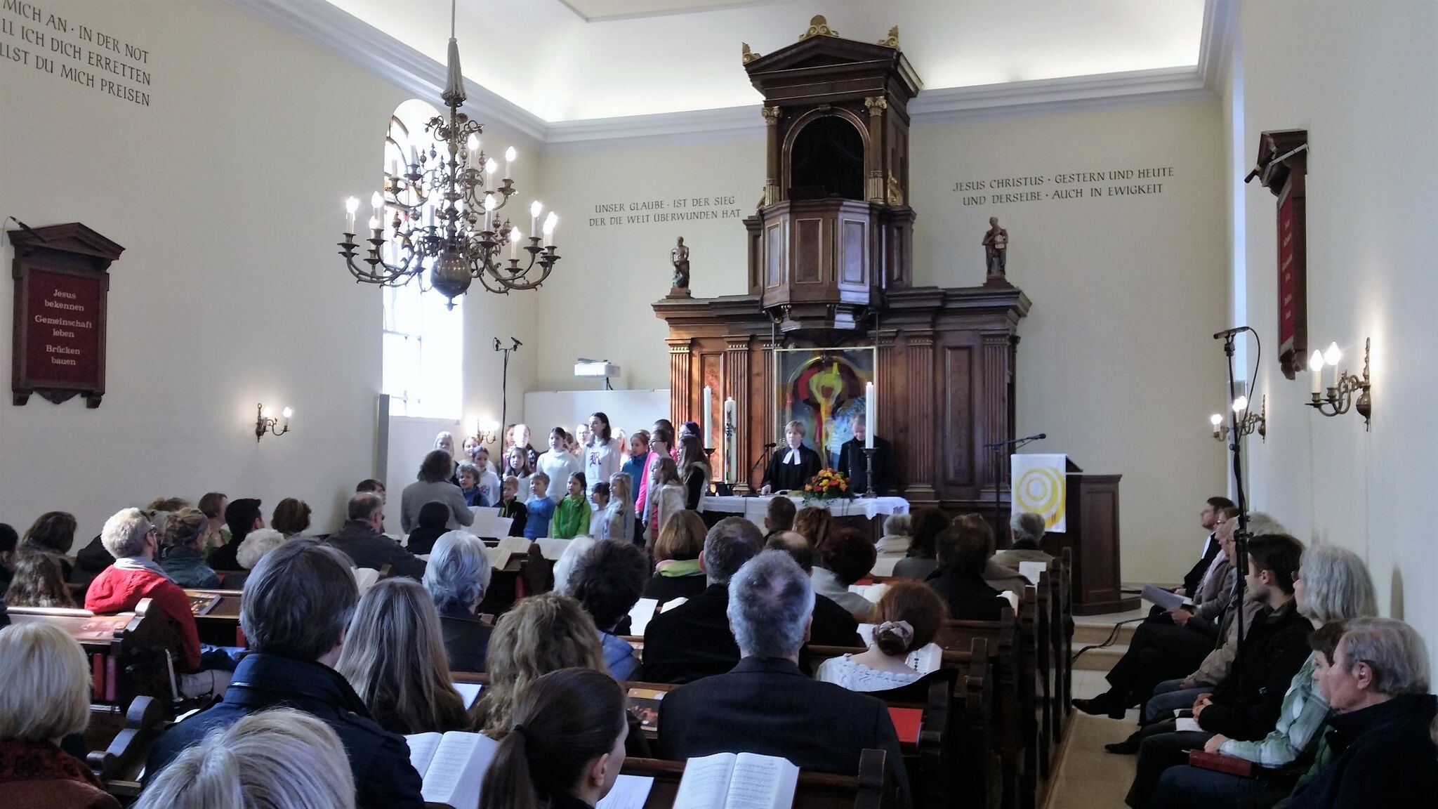 Interior view of a church during a service with a choir and a preacher at the altar.