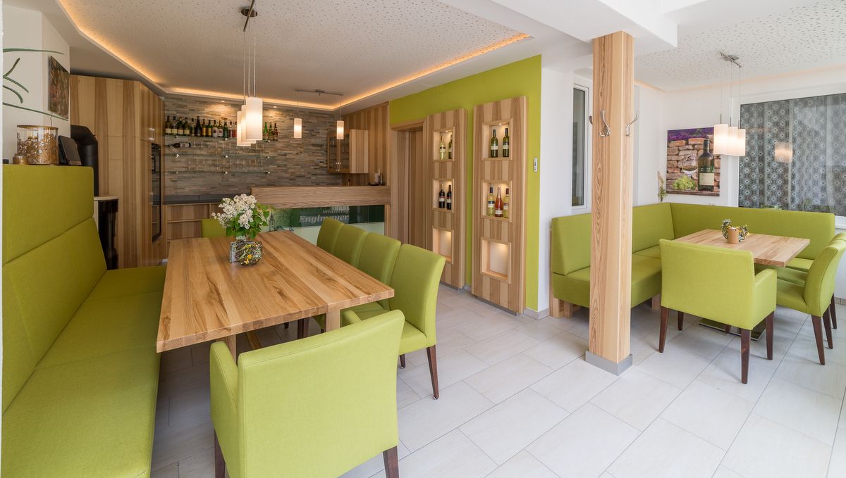 Modern tasting room with wooden tables and green upholstered furniture.