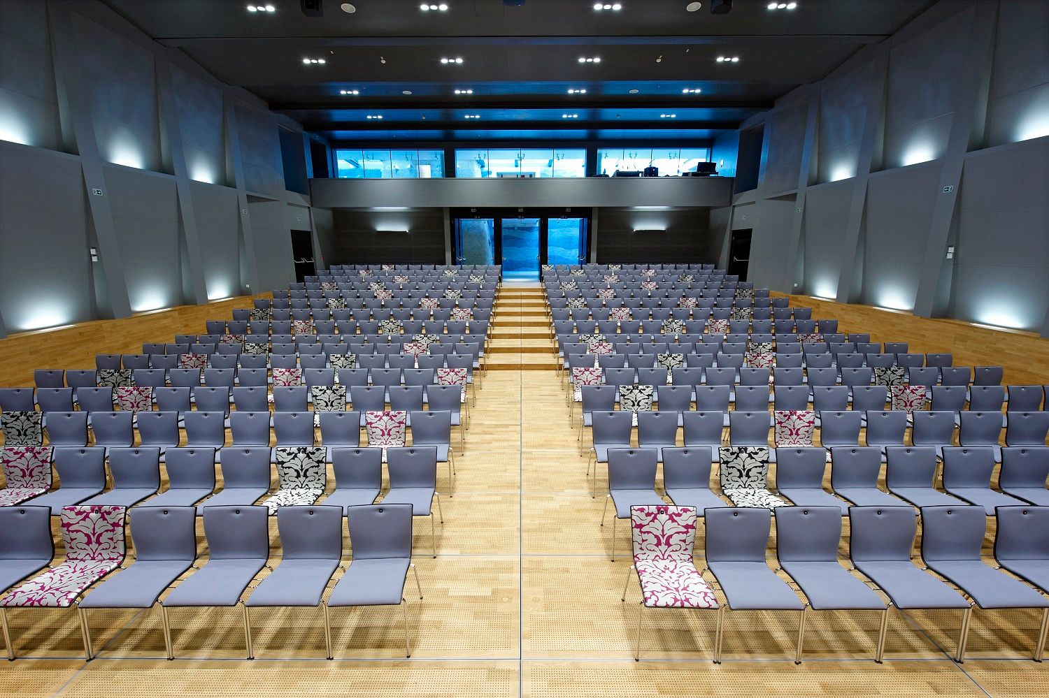 Modern hall with many empty rows of chairs, some with patterned covers.
