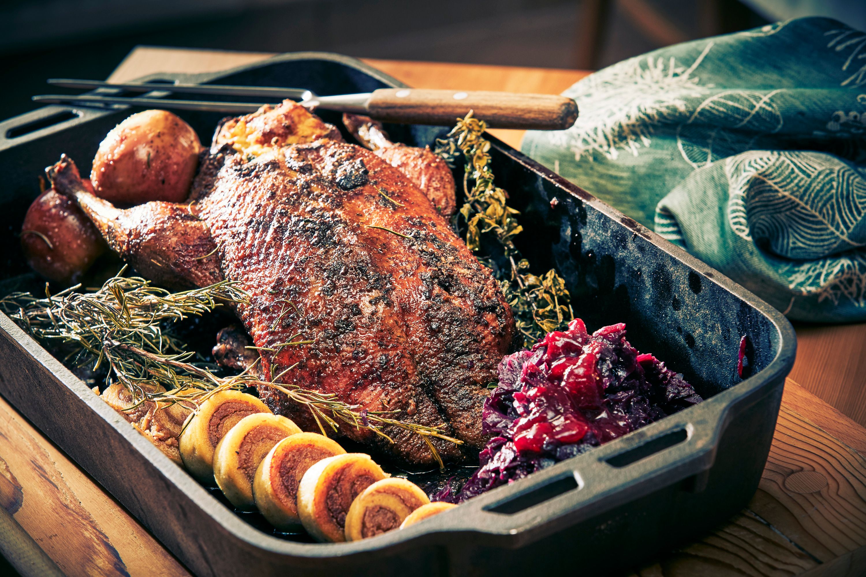 Roasted goose with side dishes in a roasting tin.