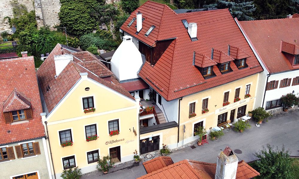 Aerial view of a yellow guest house with red roofs and flower boxes.