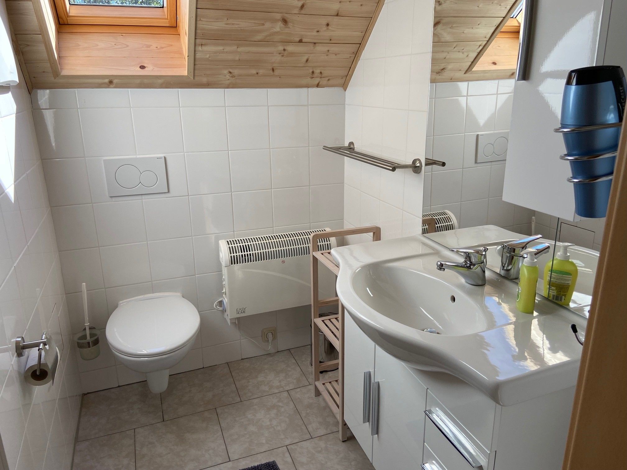 Modern bathroom with skylight, washbasin, toilet and towel rail.